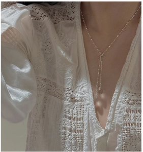 Detailed view of an S925 sterling silver Y-shaped necklace with white crystal beads on a model