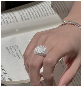 Macro detail of retro S925 sterling silver rose flower relief ring on finger