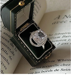 Macro shot of cushion-cut white crystal ring in vintage green velvet jewelry box