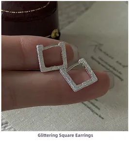 Macro detail of silver square hoop earrings with a textured glitter finish