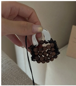 Macro detail of a vintage woven handbag pendant made of dark wood beads and matte silver