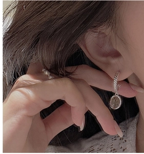 Close-up of vintage S925 silver twist hoop earrings with coin pendant on model
