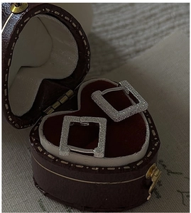 Macro shot of silver square glitter hoop earrings in a vintage red heart-shaped jewelry box