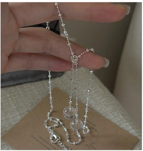 Detailed macro of silver necklace with clear crystal ball pendants and flower beads