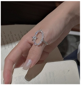 Nahaufnahme des S925 Sterlingsilber Sternrings mit Zirkonia-Inlay auf Hand und Buchhintergrund
