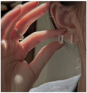 Detail view of silver geometric rectangle earrings with a brushed matte metallic texture