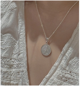 Detail of S925 sterling silver Tree of Life pendant worn on a vintage textured chain
