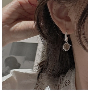 Close-up of vintage S925 sterling silver drop earrings featuring textured hoops and coin pendants