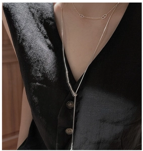 Detail of layered S925 silver long necklace and gold link chain on a black shirt
