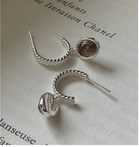 Detail of S925 sterling silver twisted hoop earrings with natural quartz stone pendant