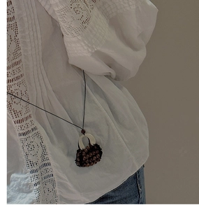 Detail of vintage hand-woven handbag pendant necklace on model with lace shirt