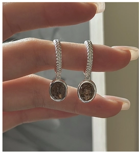 Macro view of vintage silver earrings with woven texture and oval rutilated quartz
