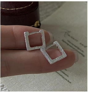 Detailed view of square silver hoop earrings with a matte shimmering texture finish