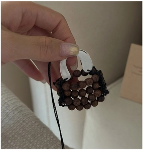 Macro detail of a handcrafted woven wooden bead mini bag pendant with silver handle