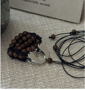 Detail of S925 silver U-shape pendant on matte brown wood beads with woven sweater chain