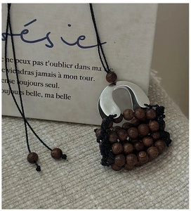 Detailed close-up of a handmade woven handbag pendant necklace on a rustic fabric background