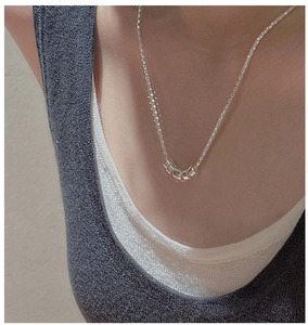 Detail of silver popcorn chain necklace with five small tubes on a female model