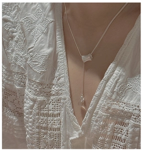 Détail du collier en argent S925 avec pendentif cristal sur chemisier en dentelle
