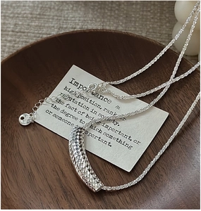 Gros plan sur collier en argent S925 avec pendentif tube à texture diamantée ciselée
