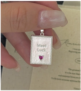 Macro detail of S925 silver square pendant with Meet Luck engraving and pink heart stone