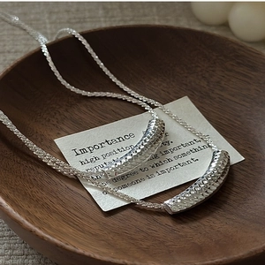 Vue macro d'un pendentif tube argenté avec texture diamantée sur une chaîne S925