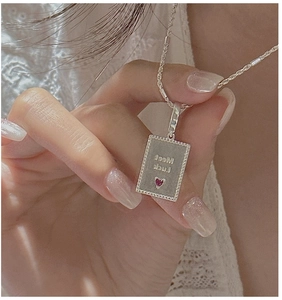 Close-up of S925 silver rectangle pendant with Meet Luck engraving and red heart gem