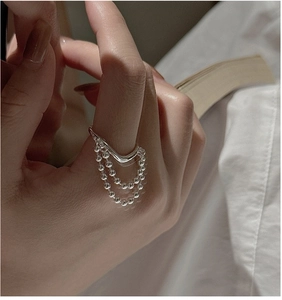 Detail of S925 sterling silver tassel ring with hanging bead chains on a finger