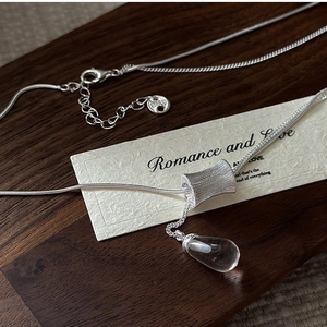 Vue macro d'un collier en argent S925 avec pendentif bambou et cristal en goutte