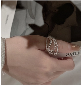Macro detail of S925 sterling silver tassel ring featuring beaded chain and smooth band