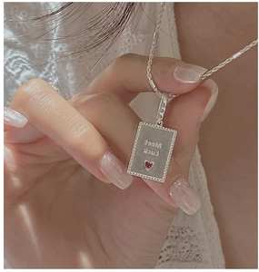 Macro detail of S925 silver rectangle pendant with red heart and Meet Luck engraving