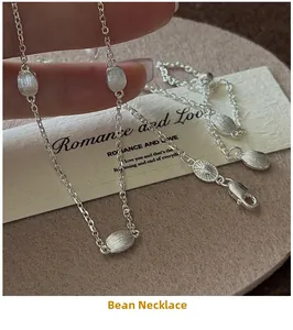 Macro shot of silver bean pendants with brushed metal texture on a delicate chain