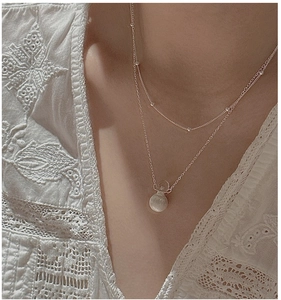 Detail of silver double layer necklace with frosted ball pendant and shimmering stone beads