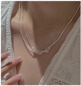 Detail of layered S925 sterling silver snake chain necklace with irregular knot pendant