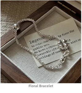 Detail of silver flower bracelet on vintage wooden box with sparkling textured chain