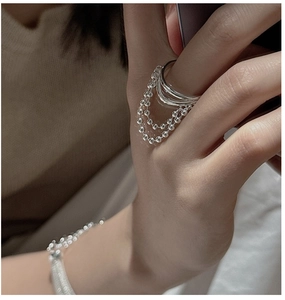 Detail of layered S925 sterling silver ring with triple tassel bead chains on hand