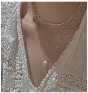 Detailed macro view of triple-layered silver S925 necklace with zircon and metal bead pendant