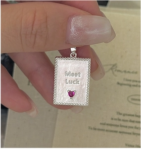 Detailed macro of S925 silver pendant featuring Meet Luck engraving and pink heart gemstone
