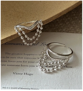 Detailed view of S925 sterling silver V-shaped rings with tassel bead chains on vintage paper