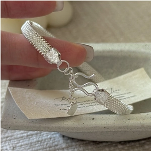 Close-up of S925 silver woven bracelet with carved floral patterns and heart pendant