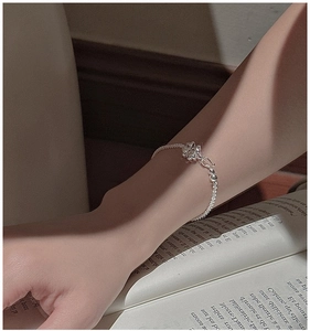 Detailed view of an S925 sterling silver four-leaf clover bracelet on a model wrist