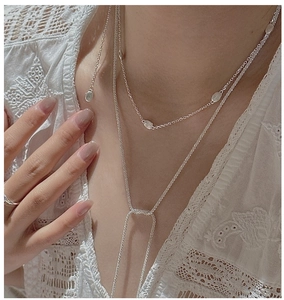 Detail of layered S925 sterling silver bean pendant necklace and Y-shaped tassel chain