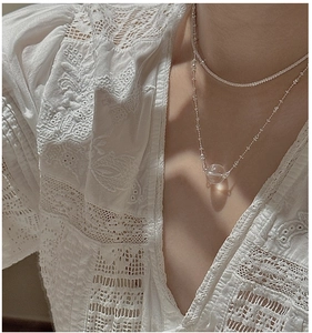 Detail of layered S925 sterling silver necklace with clear crystal pendant on model