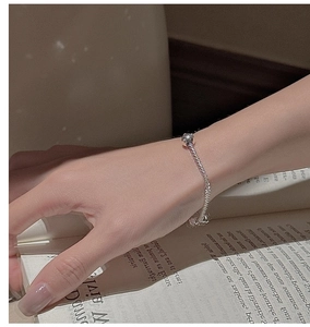 Detail of S925 sterling silver beaded bracelet with round pendant over an open book