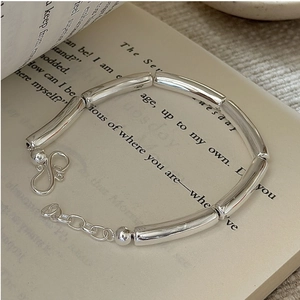 Macro detail of S925 sterling silver tube bracelet with S-hook clasp on vintage book