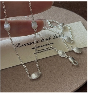 Detailed close-up of brushed silver bean pendants on a minimalist S925 sterling silver chain