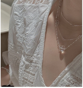 Detail view of layered S925 sterling silver chain with white crystal pendant on neck