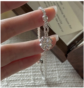 Macro shot of silver clover charm bracelet on wrist with elegant jewelry box