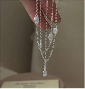 Detailed close-up of multi-layer S925 silver necklace with brushed oval bean pendants