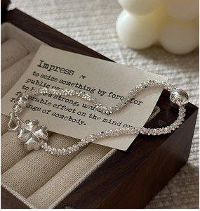 Macro detail of S925 sterling silver clover pendant and sparkling twisted chain bracelet