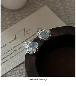 Macro detail of S925 sterling silver textured earrings with round blue gemstone